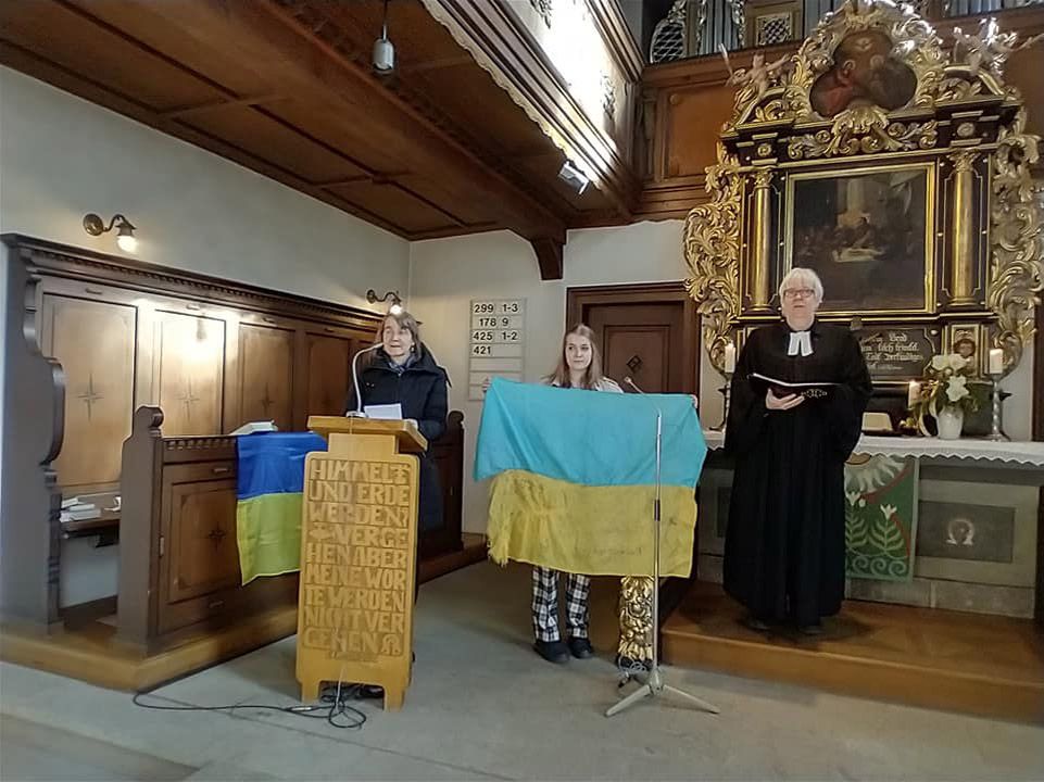 Німецький пастор молиться з прапором, привезеним з передової