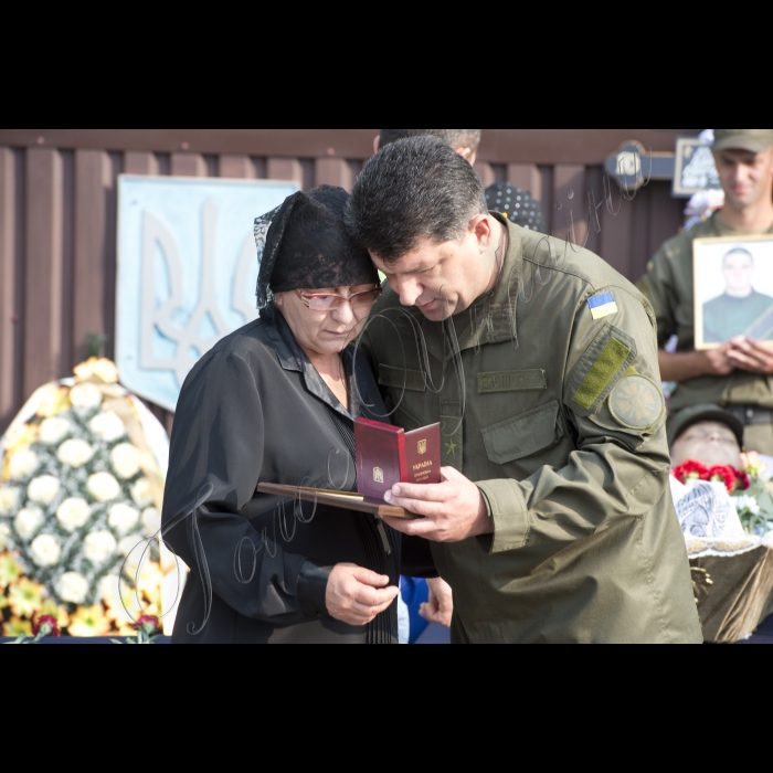03 вересня 2015
Голова ВР України Володимир Гройсман взяв участь у церемонії прощання із військовослужбовцями Дмитром Сластніковим та Олександром Костиною, які загинули від отриманих поранень під час сутичок під будівлею Верховної Ради України 31 серпня (військова частина №3027 Національної гвардії України, с. Нові Петрівці).
Заступник командувача Національної гвардії України по роботі з особовим складом генерал-майор Ярослав Сподар вручає посмертну нагороду орден «За мужність» III ступеня родичці Дмитра Сластнікова