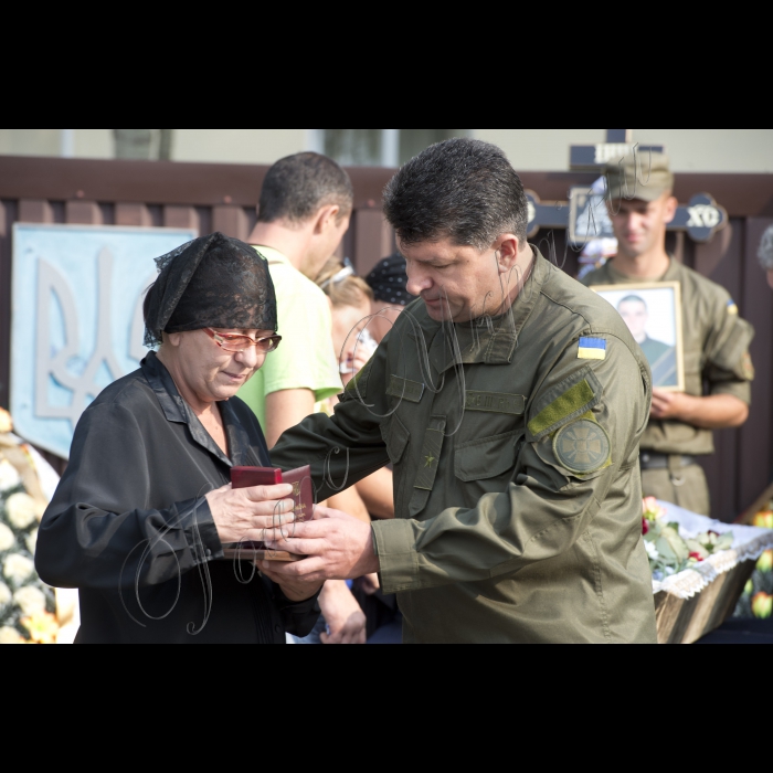 03 вересня 2015
Голова ВР України Володимир Гройсман взяв участь у церемонії прощання із військовослужбовцями Дмитром Сластніковим та Олександром Костиною, які загинули від отриманих поранень під час сутичок під будівлею Верховної Ради України 31 серпня (військова частина №3027 Національної гвардії України, с. Нові Петрівці).
Заступник командувача Національної гвардії України по роботі з особовим складом генерал-майор Ярослав Сподар вручає посмертну нагороду орден «За мужність» III ступеня родичці Дмитра Сластнікова