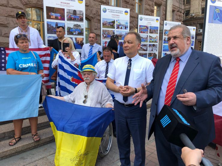 26 червня 2019 Київ. День Кримськотатарського національного прапору.  
Під стінами міськдержадміністрації та у колонному залі КМДА демонстрували світлини з виставки «Об'єднані прапором - #LIBERATECRIMEA».
Активіст Микола Подрізан, Ескендер Барієв, координатор акції “Об'єднані прапором – #LIBERATECRIMEA”, голова правління Кримськотатарського Ресурсного Центру, нар. деп. Рефат Чубаров.